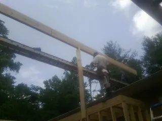 Carpenter setting a ridge beam over a new addition frame — Ice Dam Removal by Roofing Brothers in Clearbrook