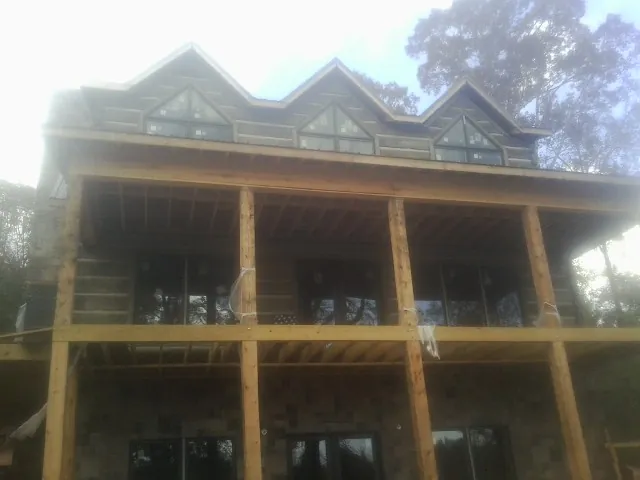 Dormers and porch framing on a large log home under construction — Roof Coating work by our crew in Clearbrook