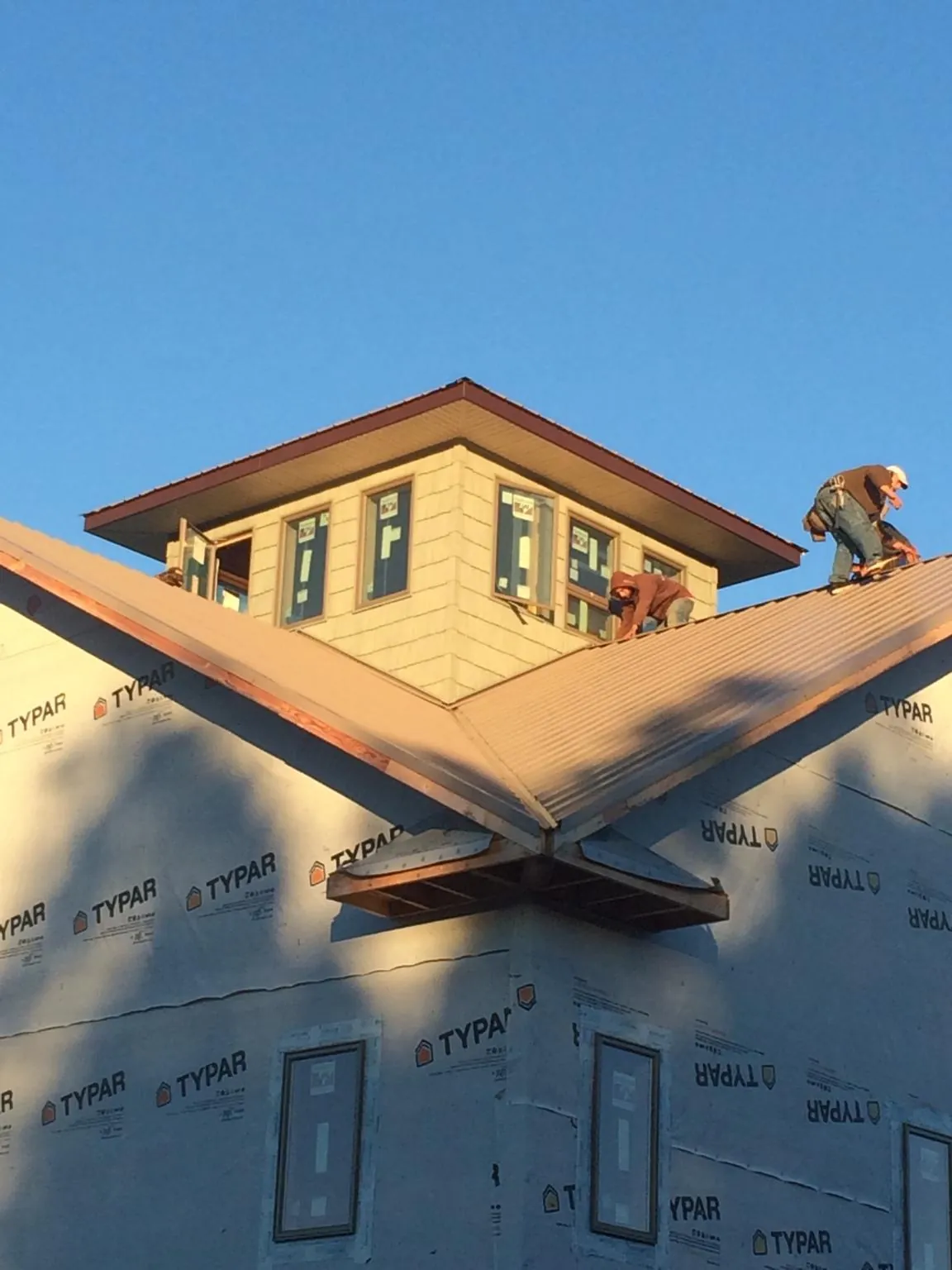 Roofers working around a rooftop cupola on a new metal roof at sunset — Roof Waterproofing in Clearbrook by Roofing Brothers